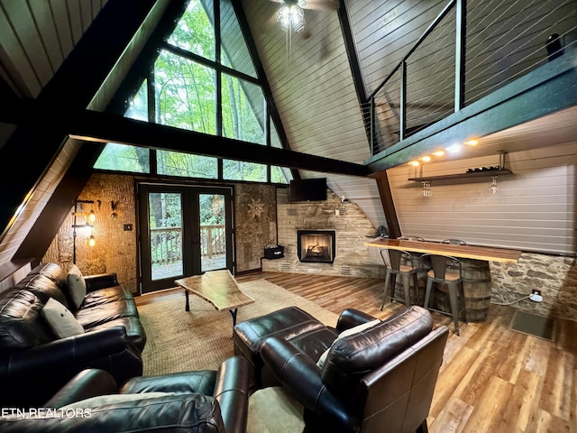 living room featuring a wealth of natural light, wooden walls, wood-type flooring, high vaulted ceiling, and a fireplace