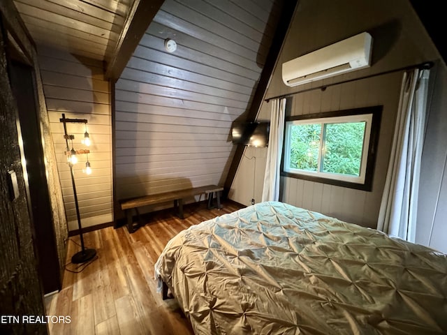 bedroom with a wall mounted air conditioner, wooden ceiling, hardwood / wood-style floors, and wooden walls