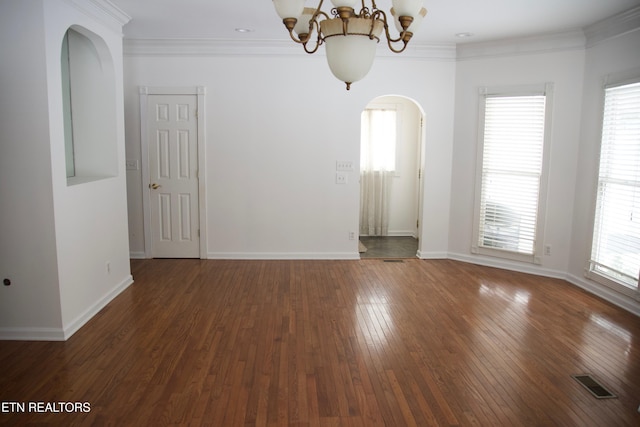 unfurnished room featuring an inviting chandelier, ornamental molding, and dark hardwood / wood-style flooring