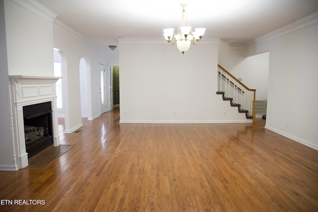 unfurnished living room with crown molding, wood-type flooring, and a notable chandelier