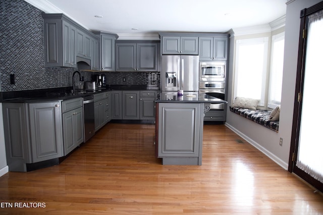 kitchen with sink, gray cabinets, appliances with stainless steel finishes, a center island, and ornamental molding