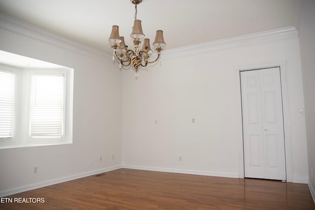 empty room featuring an inviting chandelier, ornamental molding, and dark wood-type flooring