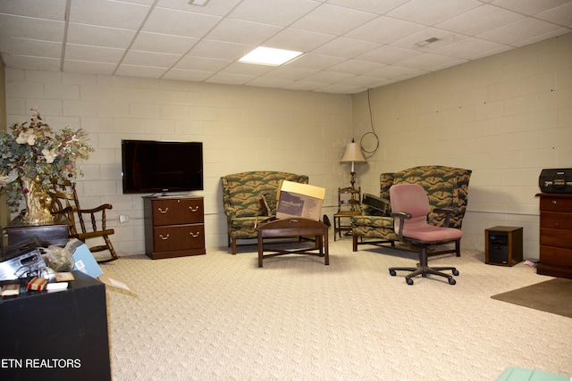 living area with a drop ceiling and carpet