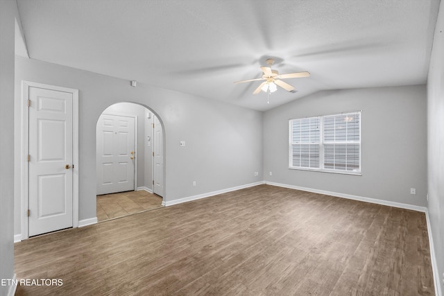 empty room with ceiling fan, lofted ceiling, and light wood-type flooring