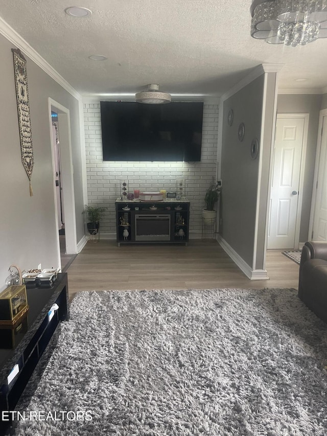 living room with crown molding, brick wall, a textured ceiling, and hardwood / wood-style flooring