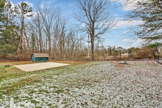 view of yard featuring basketball hoop and a storage unit