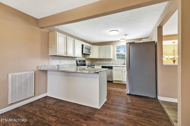 kitchen featuring light stone countertops, appliances with stainless steel finishes, white cabinetry, dark hardwood / wood-style floors, and kitchen peninsula