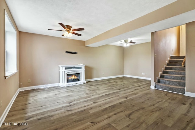 unfurnished living room featuring ceiling fan and dark hardwood / wood-style floors