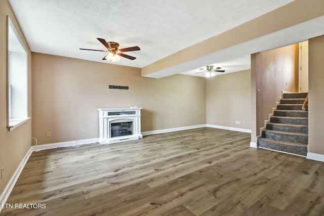 unfurnished living room featuring ceiling fan and dark hardwood / wood-style flooring