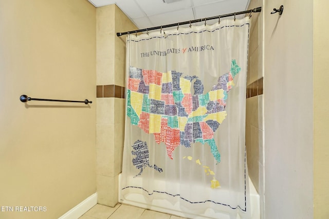 bathroom featuring a drop ceiling, tile patterned flooring, and shower / tub combo with curtain