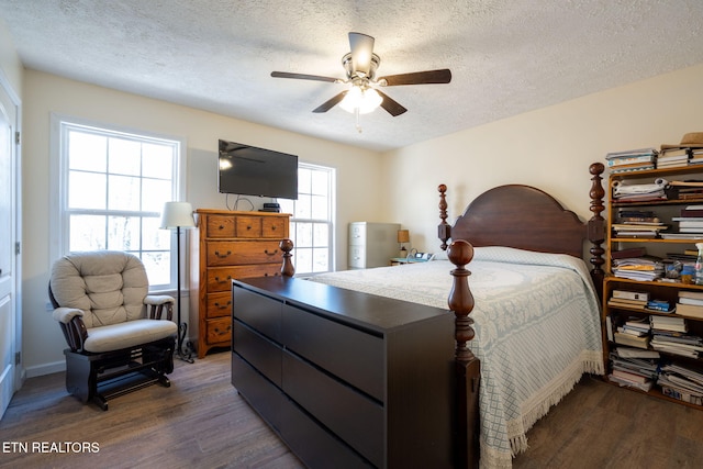 bedroom with ceiling fan, dark wood-type flooring, and a textured ceiling