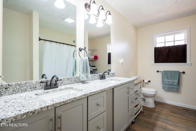 bathroom with a textured ceiling, vanity, hardwood / wood-style flooring, and toilet