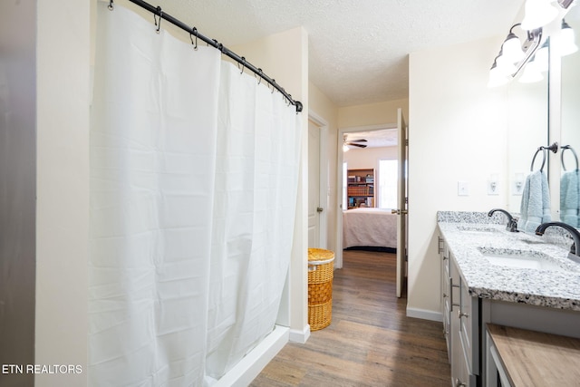 bathroom with wood-type flooring, vanity, a textured ceiling, and curtained shower