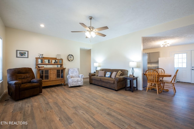 living room featuring a textured ceiling, dark hardwood / wood-style flooring, and ceiling fan