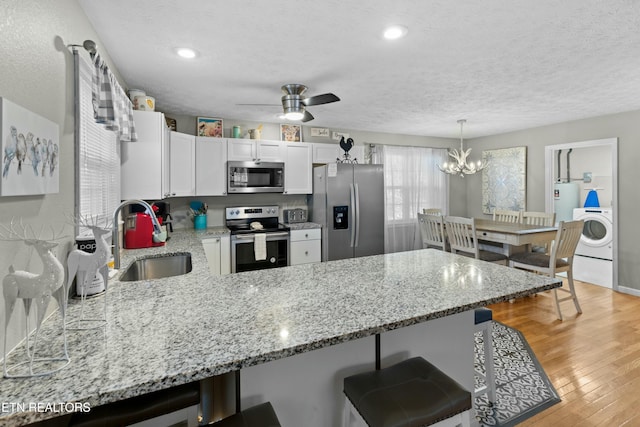 2133 Duck Pond Ln, Sevierville, TN 37876 - kitchen featuring white cabinets, washer / dryer, stainless steel appliances, sink, and hanging light fixtures