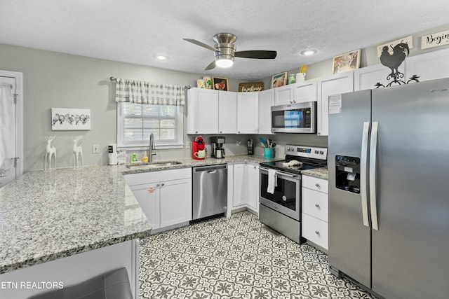 2133 Duck Pond Ln, Sevierville, TN 37876 - kitchen with kitchen peninsula, sink, white cabinetry, stainless steel appliances, and light stone counters