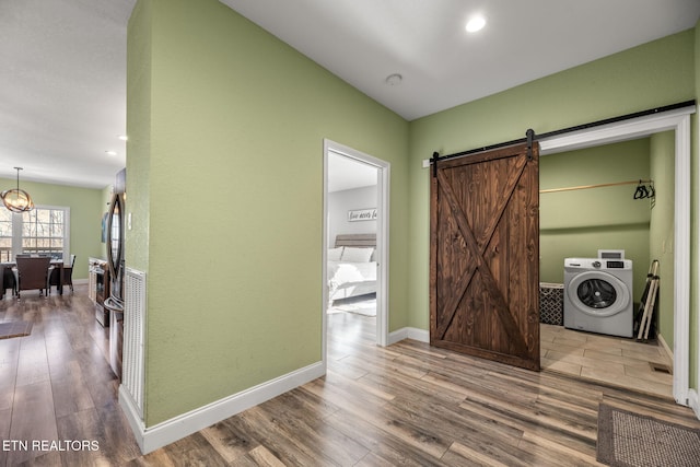 corridor with washer / clothes dryer, hardwood / wood-style floors, and a barn door