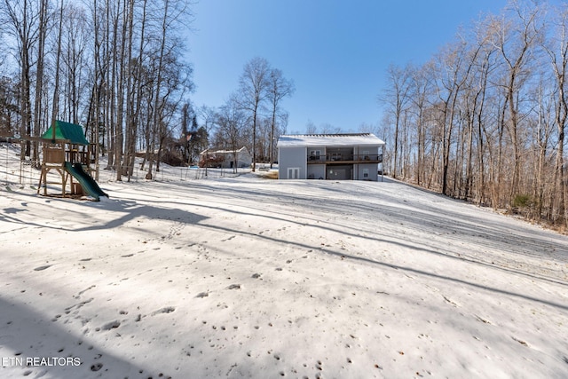 yard layered in snow featuring a playground and a garage