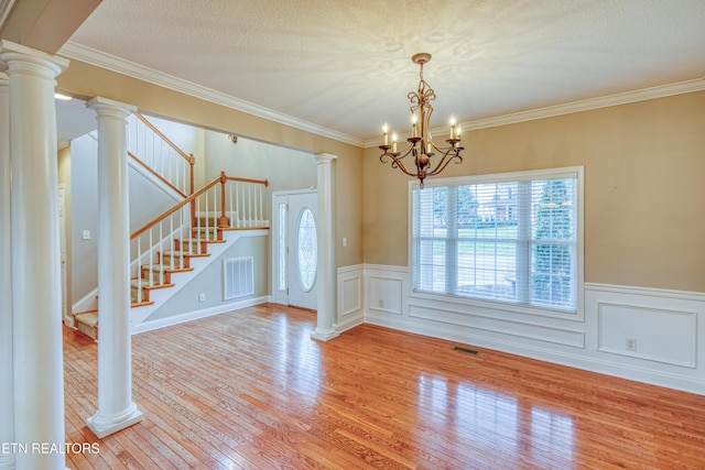 interior space with a textured ceiling, ornamental molding, light hardwood / wood-style flooring, and an inviting chandelier