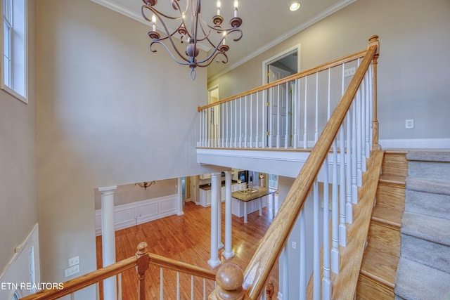 stairs with wood-type flooring, an inviting chandelier, and crown molding