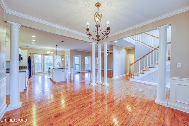 unfurnished living room with an inviting chandelier, ornamental molding, and sink