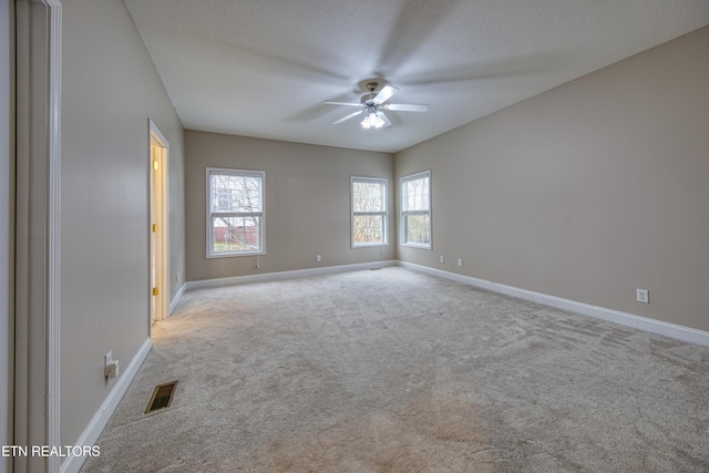 empty room featuring light carpet, a textured ceiling, and ceiling fan