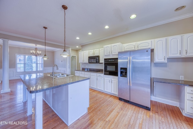 kitchen featuring pendant lighting, black appliances, sink, ornate columns, and white cabinetry