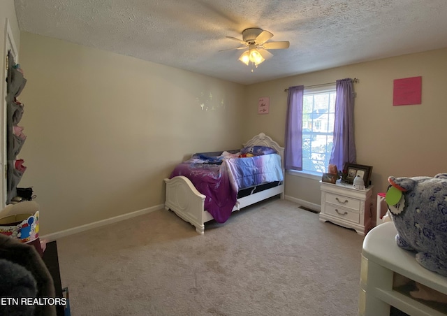 bedroom featuring ceiling fan, light colored carpet, and a textured ceiling