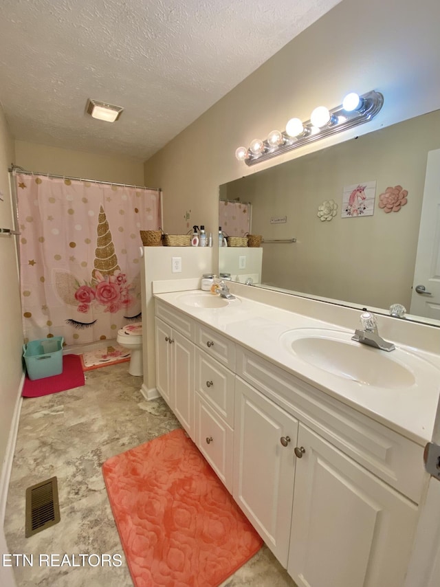 bathroom featuring vanity, toilet, and a textured ceiling