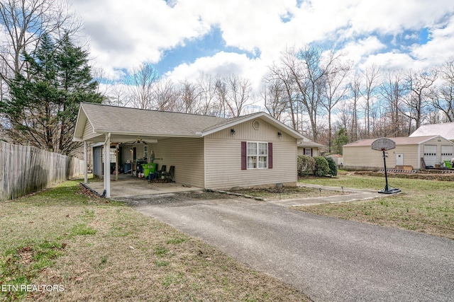 view of front facade with fence, driveway, roof with shingles, a carport, and a front yard