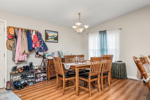 dining area featuring vaulted ceiling, wood finished floors, visible vents, and an inviting chandelier