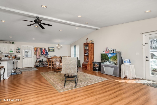 living room featuring lofted ceiling with beams, light wood-style floors, ceiling fan with notable chandelier, and recessed lighting