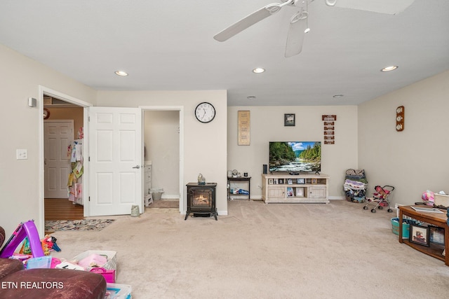 game room with carpet floors, recessed lighting, and a wood stove