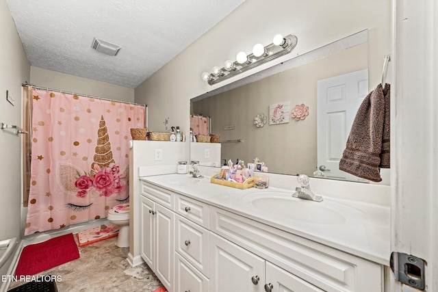 full bath with a textured ceiling, toilet, a sink, visible vents, and double vanity