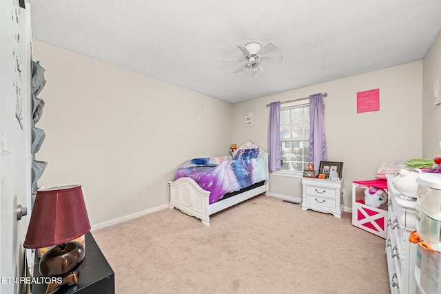 carpeted bedroom featuring a textured ceiling, a ceiling fan, and baseboards