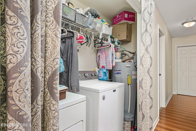 washroom with electric water heater, laundry area, separate washer and dryer, wood finished floors, and baseboards