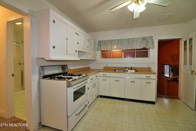 kitchen featuring sink, white cabinets, ceiling fan, and gas range gas stove