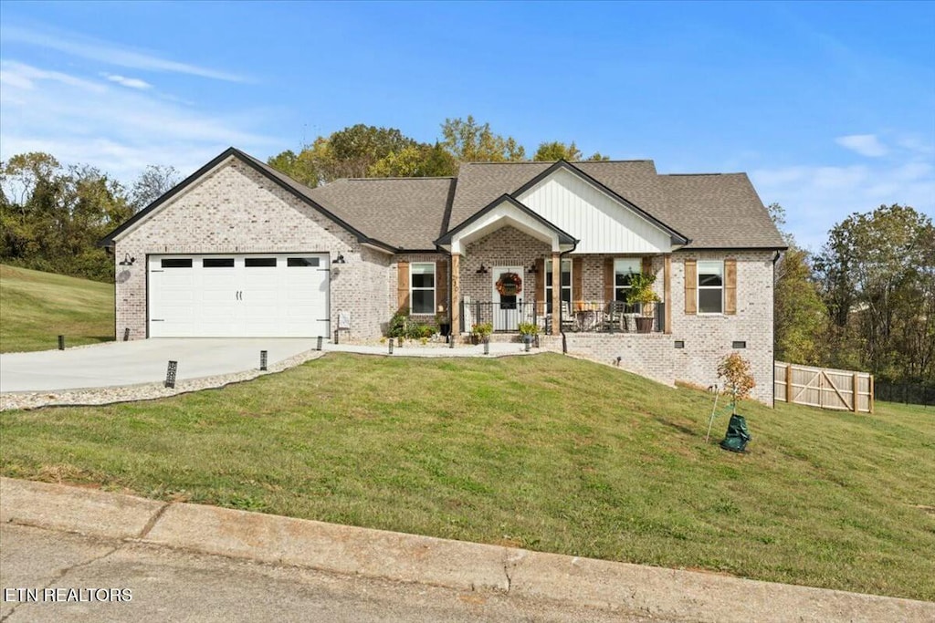 view of front facade with a front yard, a garage, and covered porch