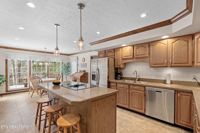 kitchen featuring a center island, crown molding, sink, appliances with stainless steel finishes, and decorative light fixtures