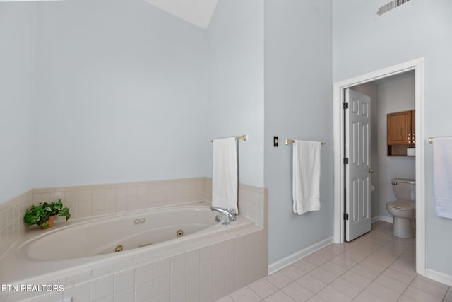 bathroom with tile patterned floors, vaulted ceiling, toilet, and tiled tub