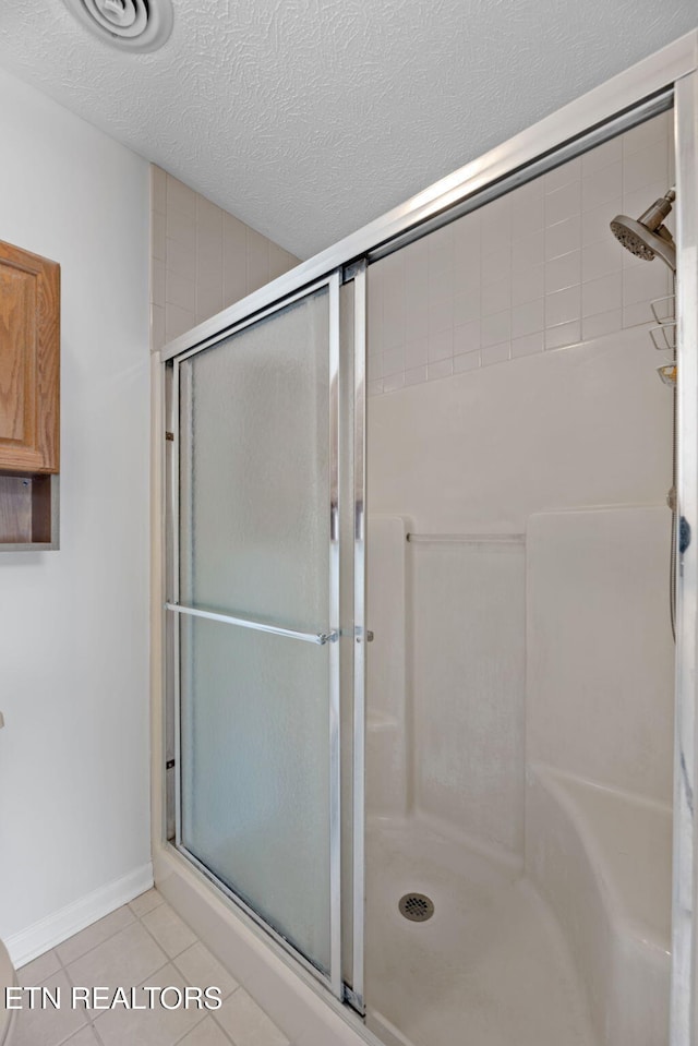 bathroom with tile patterned floors, a textured ceiling, and an enclosed shower