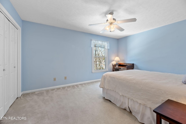 carpeted bedroom featuring ceiling fan, a textured ceiling, and a closet