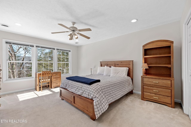 bedroom featuring a textured ceiling, light colored carpet, and ceiling fan