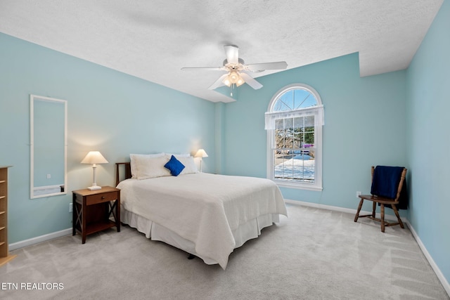 bedroom featuring ceiling fan, light colored carpet, and a textured ceiling