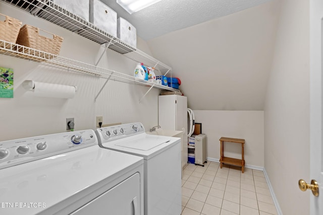 laundry room featuring light tile patterned floors, washer and dryer, and a textured ceiling