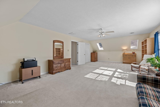 interior space featuring ceiling fan, light colored carpet, and lofted ceiling with skylight