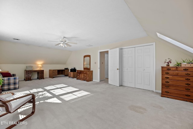 additional living space with ceiling fan, light colored carpet, and lofted ceiling with skylight