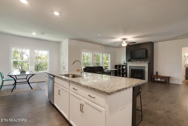 kitchen featuring light stone countertops, ceiling fan, sink, an island with sink, and white cabinets