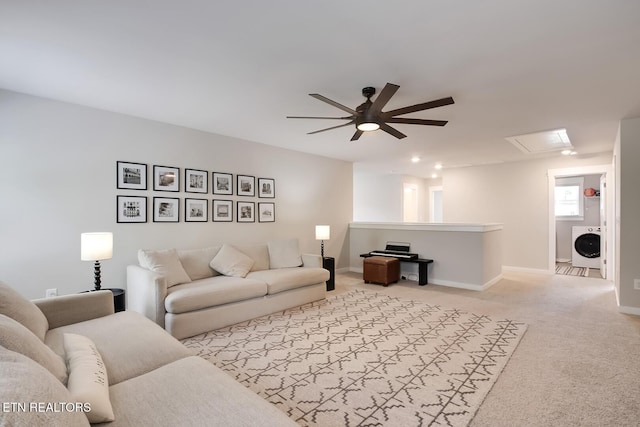 living room featuring washer / clothes dryer, ceiling fan, and light colored carpet