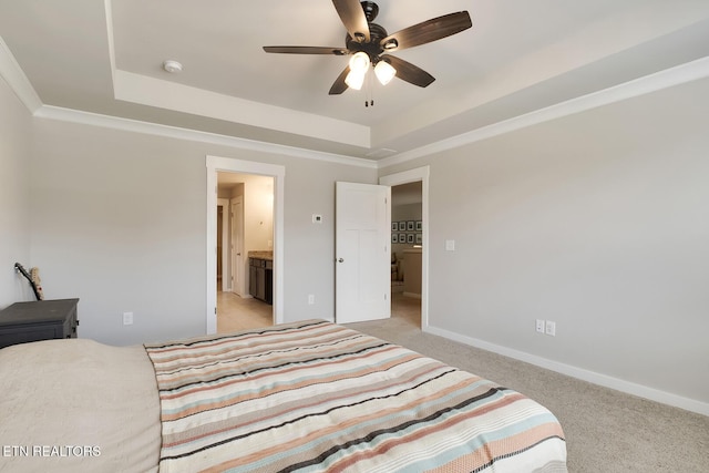 carpeted bedroom featuring a raised ceiling, connected bathroom, ceiling fan, and ornamental molding